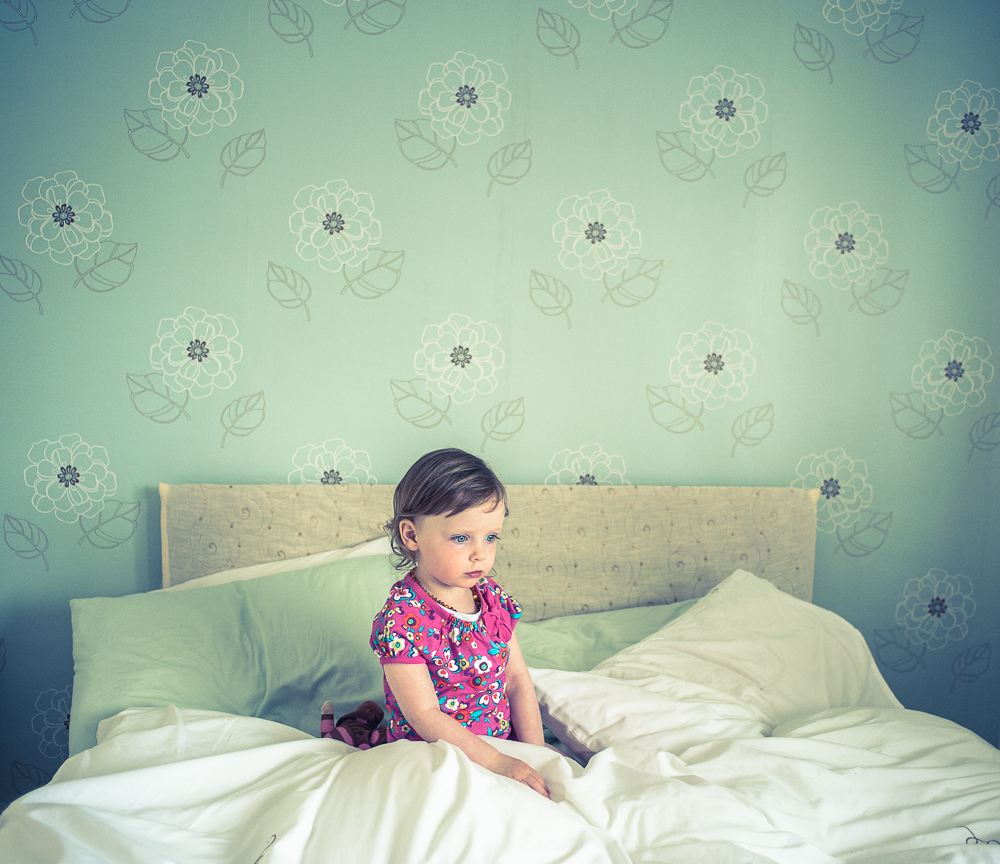 A girl sat in bed looking thoughtful